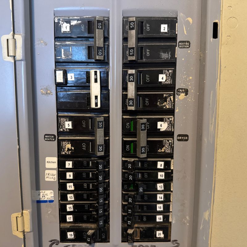Close-up of damaged electrical breakers with signs of corrosion and burn marks inside a circuit panel.
