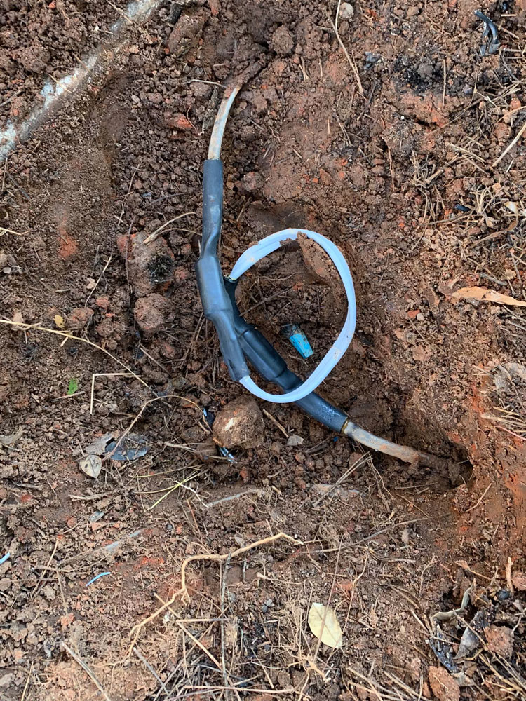 Tankless water heater and electrical conduits mounted on a brick exterior wall with exposed wiring.