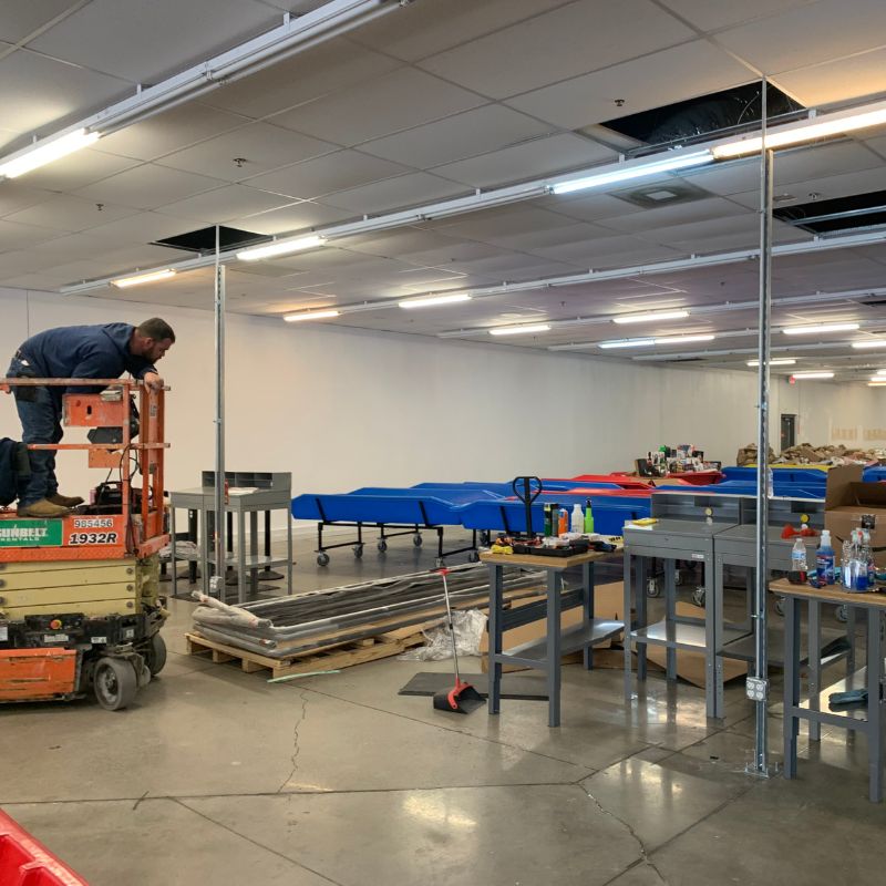 Electrician using a power drill to install wiring in an outdoor electrical panel on a brick wall.