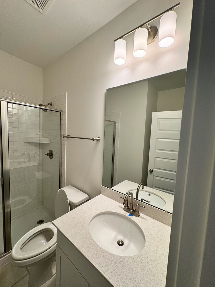 Tankless water heater and electrical conduits mounted on a brick exterior wall with exposed wiring.