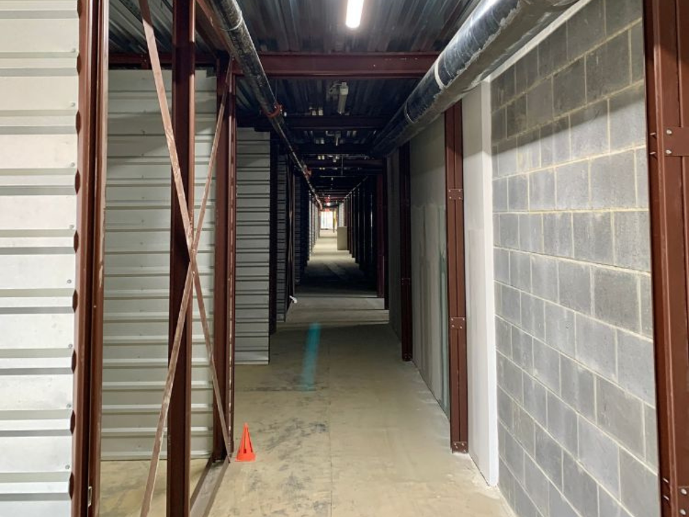 Tight corridor framing complete — conduit and lights going in along the new fire-rated path.